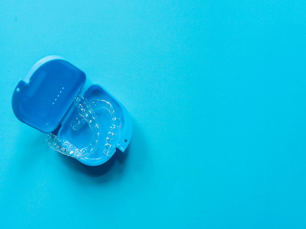 a set of clear aligners in a blue travel case on a aqua blue background