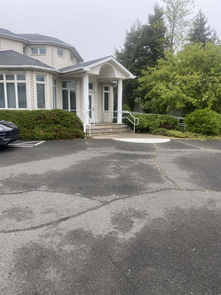 The image shows the exterior of the C. Anthony LoPresti dental office, featuring a white brick facade, tall windows, and a front entrance with white columns, a glass door, and a semi-circle patterned pavement leading to the steps.